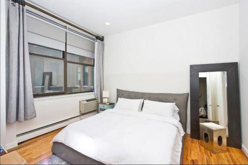 sypialnia z białym łóżkiem i dużym oknem w obiekcie Amazing 1300sf Loft By Union Sq w Nowym Jorku