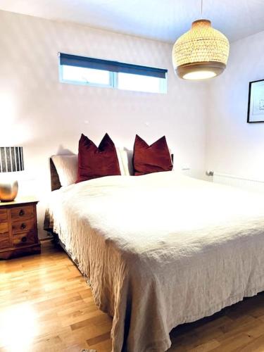 1 dormitorio con 1 cama blanca grande con almohadas rojas en Lovely 2 bedroom apartment with a large own patio en Garðabær