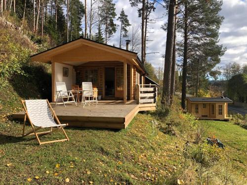 une petite cabine avec une terrasse et des chaises dans l'herbe dans l'établissement Ferienhaus in Västerrå mit Garten und Terrasse, 