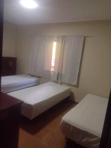 2 Betten in einem kleinen Zimmer mit Fenster in der Unterkunft Casa centro Itupeva hopii wet in Itupeva