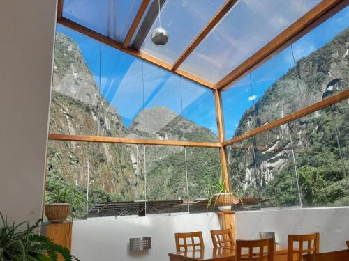 um quarto com uma grande janela com montanhas ao fundo em Fenix Hotel Machupicchu by Bruno's em Machu Picchu