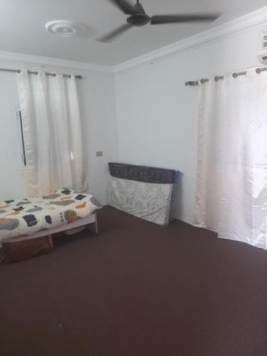 1 dormitorio con 1 cama y 2 ventanas con cortinas en بيت او منزل للإيجار اليومي والاسبوعي في جعلان بو علي, en Al Bulaydah