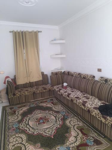 a living room with two couches and a rug at بيت او منزل للإيجار اليومي والاسبوعي في جعلان بو علي in Al Bulaydah