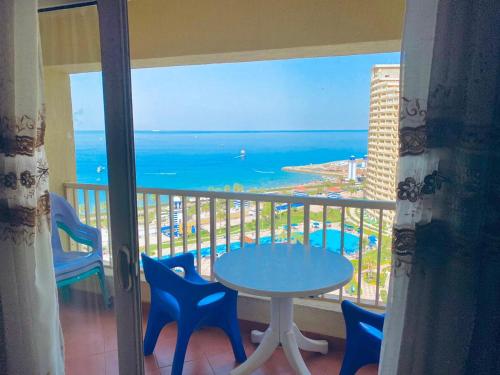 balcón con mesa, sillas y vistas al océano en porto sokhna Pyramids Apartment Familis en Ain Sokhna