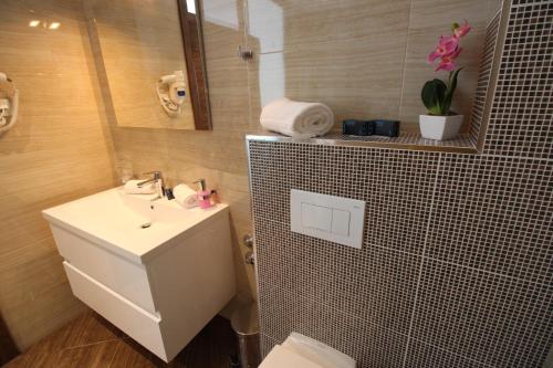 a bathroom with a sink and a toilet and a mirror at Hotel Royal Gold City - Hotel Ruža in Sarajevo