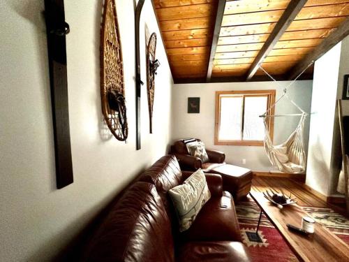 sala de estar con sofá de cuero marrón y ventana en Iron Gate Chalet - 5 Minutes to Smugglers Notch! en Cambridge