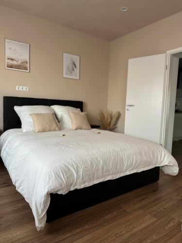 1 dormitorio con 1 cama grande con sábanas blancas en Modernes Apartment am Dreiländereck, en Alsdorf