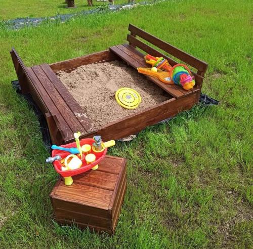 a sandbox with a bench and toys in the grass at Domek pod Dębami Bogaczewo in Bogaczewo