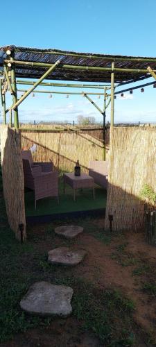 eine Pergola mit einer Bank und einem Tisch auf einem Feld in der Unterkunft Chez Elvis et Agnès 