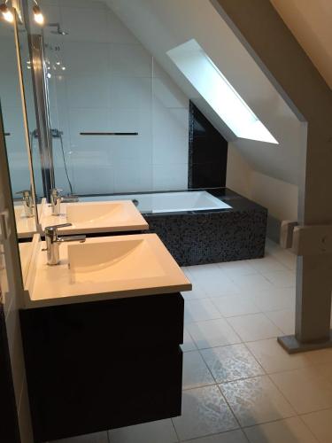une salle de bain avec deux lavabos et une baignoire dans l'établissement Maison contemporaine 230m2 Pegasus, à Bénouville