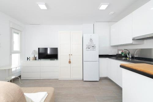 a white kitchen with white cabinets and a refrigerator at DREAMY BEACH PENTHOUSE in Torre de Benagalbón