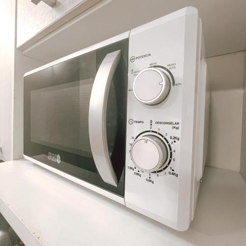 a microwave oven with its door open on a shelf at Departamento bonito y acogedor cerca de todo! in Asuncion