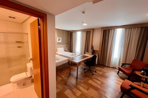 een kamer met een badkamer, een bureau en een toilet bij Apto Executivo no Intercity in Manaus