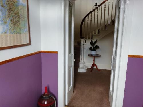 einen Flur mit lila und weißen Wänden und einer Treppe in der Unterkunft Ferienhaus für 6 Personen ca 100 qm in Crianlarich, Schottland Loch Lomond and the Trossachs Nationalpark in Crianlarich