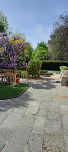 uma passagem de pedra com flores roxas num jardim em Villa Lina em Cremona