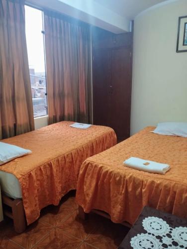 2 camas en una habitación con ventana en Departamento amoblado Santa Beatriz, en Tacna