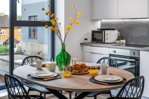 a wooden table with a vase of flowers and food on it at Modern 2 bed in Potters Bar - with FREE Parking- 4 min walk from the TRAIN STATION - DIRECT TRAINS TO LONDON in Potters Bar