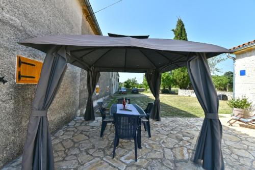 Ferienhaus für 5 Personen ca 66 qm in Kršanci, Istrien Binnenland von Istrien في Pifari: طاولة وكراسي تحت مظلة كبيرة