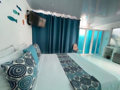 a bedroom with a bed with a blue curtain at Posada Sunrise View in Providencia