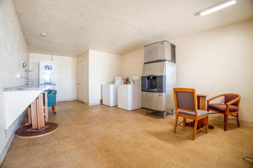 a kitchen with a refrigerator and a table and chairs at Holiday Motel, Lordsburg By OYO in Lordsburg