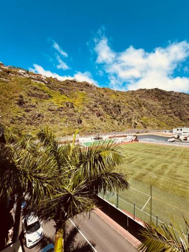 a tennis court with palm trees in front of a mountain at VALE MAR Guest in Ribeira Brava