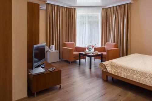 a hotel room with a bed and chairs and a television at Residence Odesskij Dvorik in Odesa