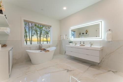 ein weißes Bad mit einer Badewanne, einem Waschbecken und einem Fenster in der Unterkunft Paradise Peninsula by AvantStay Waterfront Private Beach Hot Tub View in Mooresville