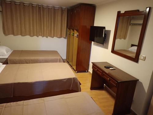 a hotel room with two beds and a mirror at Louran Residence Hotel Apartments in Alexandria