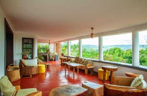 a living room with chairs and tables and large windows at Rutete Eco Lodge in Rwinkwavu