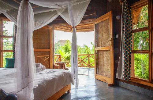 a bedroom with a canopy bed and a large window at Rutete Eco Lodge in Rwinkwavu