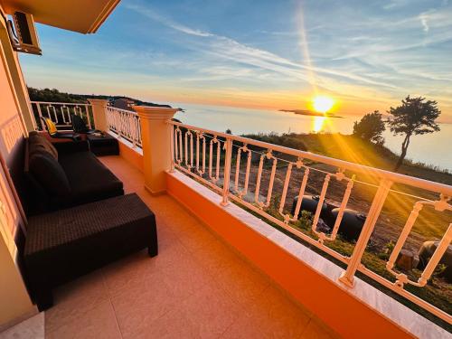 a balcony with a view of the ocean at sunset at Nikos Apartments Corfu in Agios Stefanos