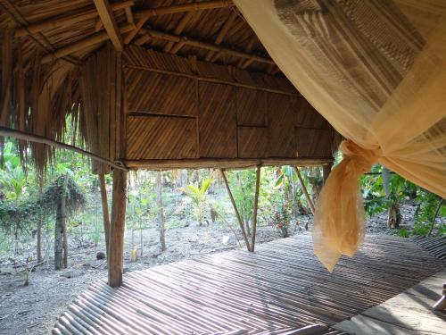 une terrasse couverte en bois avec un rideau et une promenade en bois dans l'établissement Eco-Camping Mango Feliz Rincón del Mar, à San Onofre