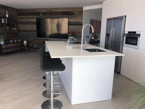 a kitchen with a white counter with a sink and a bar at Luxury apartment with stunning terrace and with heated pool in Adeje