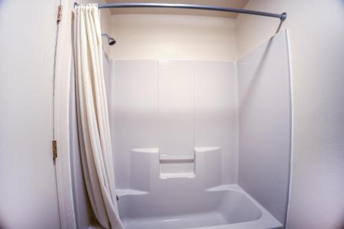 a white shower with a shower curtain in a bathroom at Holiday Motel, Lordsburg By OYO in Lordsburg