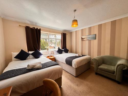 a hotel room with two beds and a chair at High Trees Guest House Gatwick in Hookwood