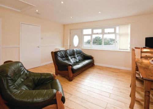 a living room with two leather chairs and a couch at Anglesey Bungalows in Trearddur