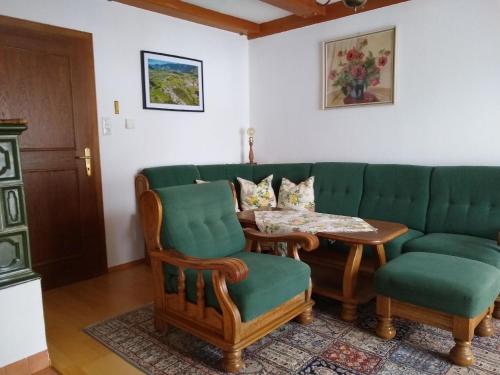 a living room with a green couch and a table at Haus Bernkogelblick in Goldegg