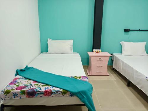2 Betten in einem Zimmer mit einem Nachttisch und einem 6 x 6 cm großen Bett in der Unterkunft Casa Mango in Cali