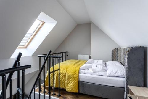 uma cama com um cobertor amarelo num sótão em Apartament B28 Green Resort dwupoziomowy z Basenem, Sauną, Jacuzzi - 5D Apartments em Szklarska Poręba