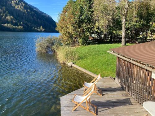 a couple of chairs sitting on a dock next to a lake at Apartment mit Seeblick in Feld am See