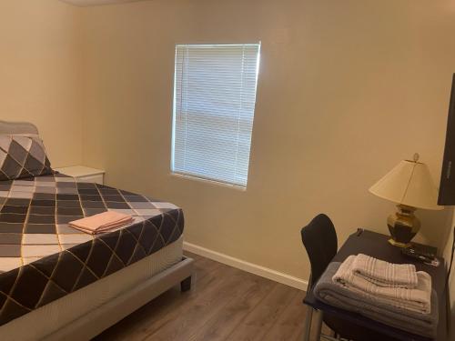 a bedroom with a bed and a table and a window at Private Queen Bedroom C shared common spaces in Fort Pierce