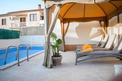 un patio con sillas y una sombrilla junto a la piscina en Ferienwohnung für 6 Personen ca 100 qm in Marčana, Istrien Südküste von Istrien, en Marčana