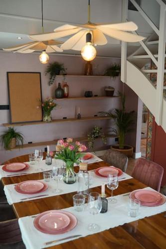 a dining table with pink plates and flowers on it at Het Warme nest in Noordwijkerhout