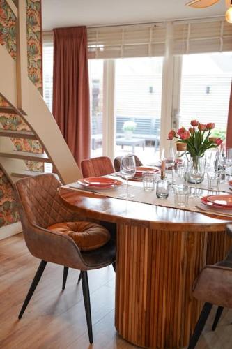 a dining room with a table with glasses and flowers at Het Warme nest in Noordwijkerhout