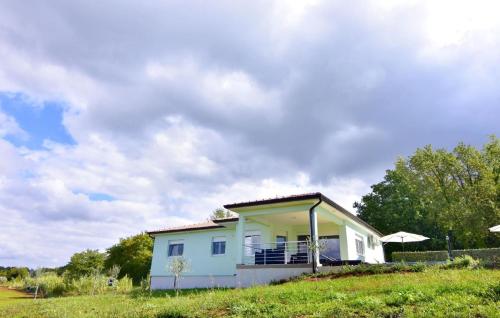 ein kleines weißes Haus auf einem Grashügel in der Unterkunft Großes Ferienhaus in Buroli mit Privatem Pool in Buroli