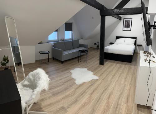 a bedroom with a bed and a couch and wooden floors at Modernes Loft am Dreiländereck in Alsdorf
