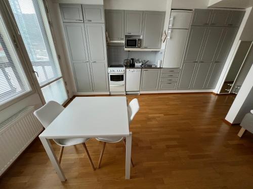 a white kitchen with a white table and chairs at Studio next to Sello and Leppävaara train station in Espoo