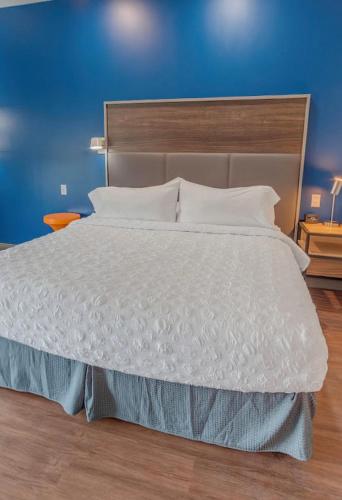 1 dormitorio con 1 cama blanca grande y pared azul en Tru By Hilton, en Santee