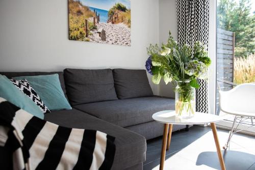ein Wohnzimmer mit einem Sofa und einem Tisch mit einer Blumenvase in der Unterkunft Ferienhaus in Pobierowo mit Terrasse, Garten und Grill in Pobierowo