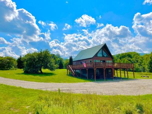 a large house on a grassy field with a sky at Journeys End Chalet - Minutes to Jay Peak! in Jay